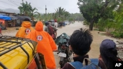 Người dân Philippines đi qua một đoạn đường ngập lụt do bão gây ra.