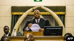 ဇင်ဘာဘွေ လွှတ်တော်ဥက္ကဋ္ဌ Jacob Mudenda က သမ္မတ Robert Mugabe တရားစွဲဆိုရေး နိုဝင်ဘာ ၂၁ ရက်နေ့က လွှတ်တော်ကို ဖတ်ကြားပြနေစဉ်။