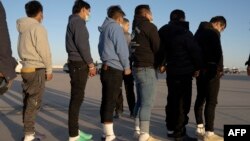 美国国防部发布的这张照片显示,2025年1月23日,戴着手铐镣铐的无证移民准备在德克萨斯州布利斯堡登上C-17军用运输机。