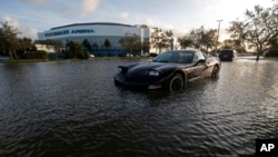 Một chiếc xe ngập trong nước ở Estero, Florida, hôm 11/9 và phía xa là sân vận động Germain Arena, nơi lánh nạn của người dân.