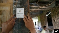 资料照片:2024年10月1日,缅甸内比都,一名人口普查员在收集信息后在一所房子的入口处贴上贴纸。缅甸正在举行全国人口普查,以汇编2025年大选的选民名单。