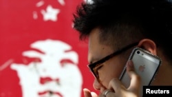 在北京有人用苹果手机打电话,旁边是雷锋画像(2013年7月24日)。