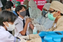 A student reacts as a medical worker administers a shot of the Sinovac COVID-19 vaccine during a vaccination campaign for children ages 12-17 at a school in Tangerang, Indonesia, July 14, 2021.
