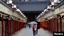 东京市民戴着口罩走在关闭的商店旁。(2021年5月7日)