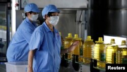 资料图片：2018年7月4日，中国一工厂工人用美国大豆提炼生产瓶装豆油。
