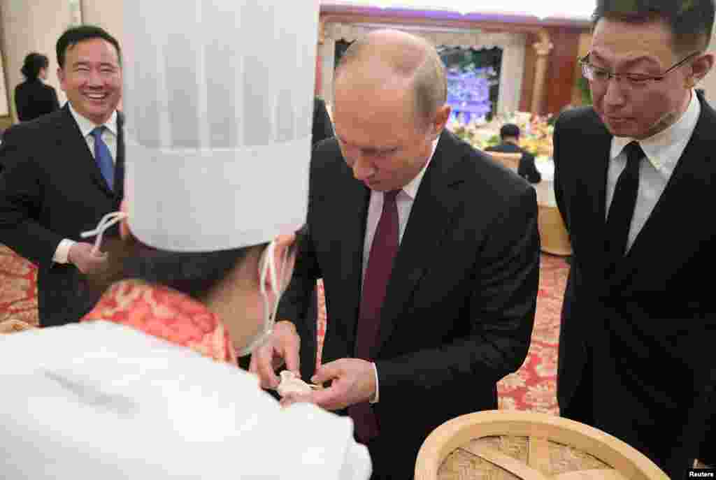 上图让人想起这张照片——俄罗斯总统普京2018年6月8日在中国天津参加招待会,学习做包子。这两幅图片一脉相承。