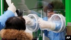 韩国医护人员在首尔给民众做新冠病毒检测。(2021年12月10日)