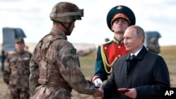 俄罗斯总统普京(右)在中俄边界附近举行的“东方-2018”战略军演后给一名中国军人颁发勋章。(2018年9月13日)