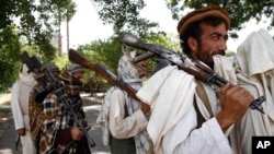 FILE – Taliban representatives are meeting this week in Oslo, Norway, with female Afghan lawmakers and peace negotiators. Here, Taliban fighters prepare to surrender weapons to Afghan authorities in Jalalabad, Afghanistan, in July 2011.