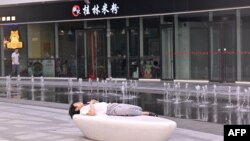 资料照：一名男子在北京一家商场的喷泉旁睡觉。（2024年7月18日）