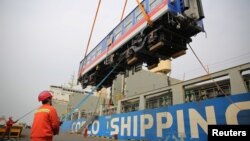 中国山东省青岛港的工人将一辆出口斯里兰卡的高铁车厢装入集装箱里。(2020年3月3日)