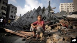 Bé trai Palestine ngồi trên đống đổ nát của tòa nhà 15 tần bị phá hủy sau các vụ không kích của Israel, ngày 26/8/2014.