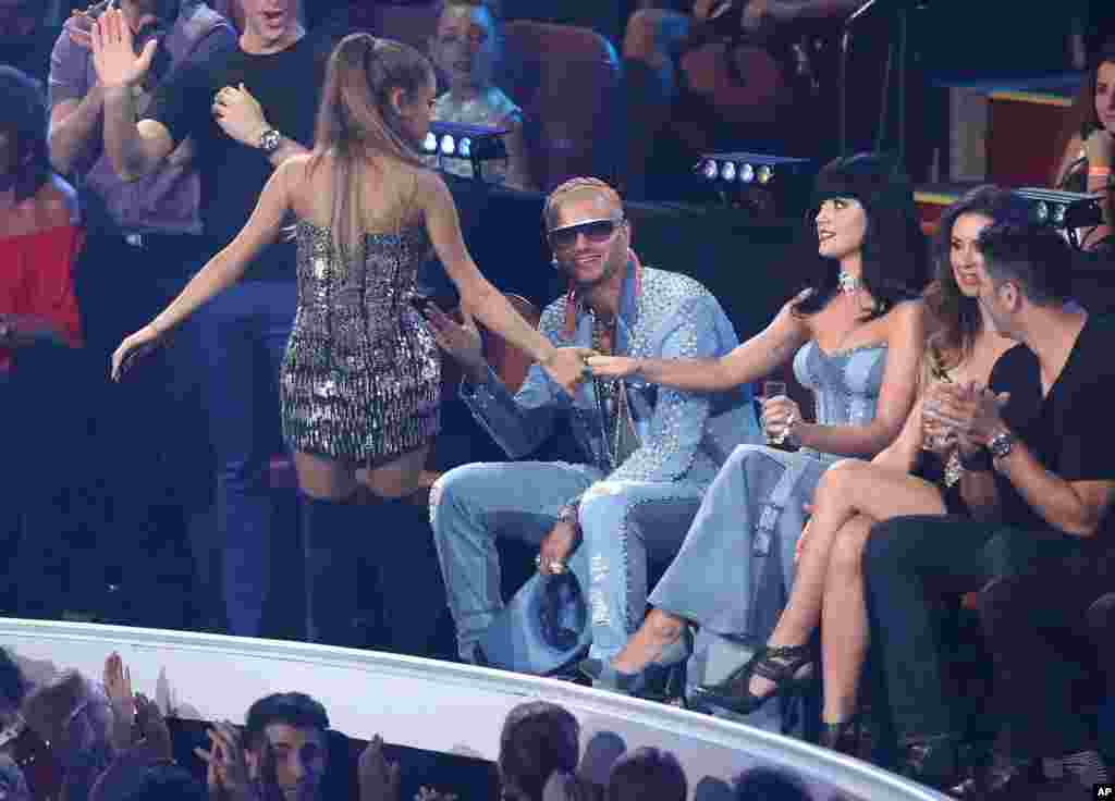 在MTV颁奖典礼上,美国流行歌星爱莉安娜·格兰德拉着歌星凯蒂·佩里(Katy Perry)的手(2014年8月24日)。凯蒂·佩里和歌星贾斯汀·比伯等人作为嘉宾曾经在2017年6月4日的曼彻斯特公益演唱会上献唱。