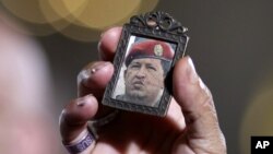Một người phụ nữ cầm bức hình Tổng thống Chavez khi người dân tập trung tại một nhà thờ ở Caracas, Venezuela để cùng cầu nguyện cho ông.