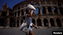 Seorang turis membawa kipas untuk menghadapi gelombang udara panas saat suhu mendekati 40 derajat Celcius di ibu kota Italia, Roma. 