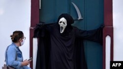 8月7日,巴西富米加一女子观看演员法比奥·德阿梅达扮演死神提请公众主义戴口罩和保持社交距离以防范病毒传播的重要性。