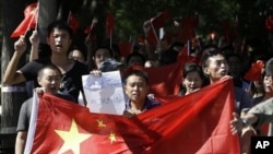 资料照片:2012年9月14日星期五,中国北京的反日抗议进入第四天,中国抗议者举着中国国旗和写着“日本狗,战败国”的纸游行到日本大使馆。