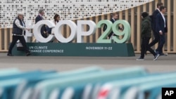 与会者走过会场外的COP29联合国气候高峰会标志。(美联社:2024年11月23日)