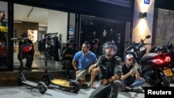 在特拉维护贾法附近的致命枪击事件现场附近,以色列警察和边防警察在空袭警报声中进入隐蔽状态。(2024年10月1日)