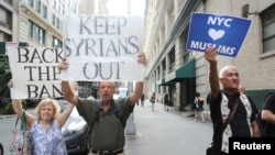 纽约,旅行禁令的支持者们举着“让叙利亚人滚出去”的标语牌回应反旅行禁令的抗议人群。(2017年6月29日)