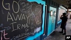 在一间已经关闭的餐馆门口的黑板上,写着希望飓风离开的文字。