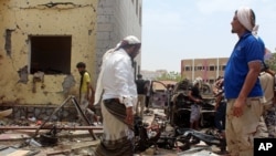 星期一,在也门南部城市亚丁,亲政府的武装人员聚集在自杀式汽车炸弹爆炸现场。(2016年8月29日)