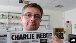 讽刺漫画刊物《查理周刊》发行总监在巴黎展示期刊头版,(2012年9月19日资料图)