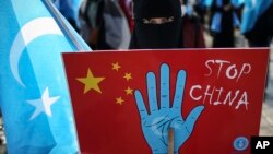 资料照:在土耳其首都伊斯坦布尔的维吾尔人手举抗议中国的标语牌参加示威集会。(2021年3月25日)
