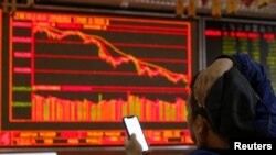 一名中国投资者坐在北京一个证券交易所的电子显示屏前。(2018年10月11日)