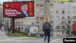 塞尔维亚一名女子走过贝尔格莱德街头树立的感谢中国领导人习近平的广告牌旁。(2020年4月1日)
