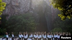 中国江苏淮安市钵池山公园的巨型老子雕像前,人们在国际瑜伽日练习瑜伽(2018年6月21日)。