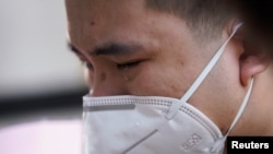 中国为死于冠状病毒病(COVID-19)的人举行全国哀悼活动,湖北省武汉市一名戴着口罩的男子哭泣。(2020年4月4日)