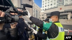 一名警察挡住记者的镜头阻止拍摄审讯公民记者张展的上海浦东新区法院外景。(2021年12月28日)