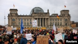 资料照片:在德国柏林的联邦议会大厦前,示威者举着“我们是人民”的标语,抗议基督教民主联盟党领袖兼总理候选人弗里德里希·梅尔茨和极右翼德国选择党的移民计划。(2025年2月2日)