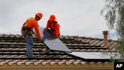 美国工人正在亚利桑那州一家住房的屋顶上安装太阳能板。(2016年6月1日)