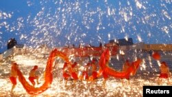 2013年2月10日在北京的一处游乐园庆祝农历新年的火龙舞表演中,火龙队员在铁水花与干花的施放中舞着火龙