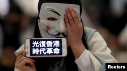 一名香港示威者在元朗地区一个商场的抗议活动中头戴面罩手举反送中运动口号。(2019年11月21日)