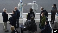 Một nhân viên mặc đồ bảo hộ hướng dẫn nhóm nhà nghiên cứu của Tổ chức Y tế Thế giới (WHO) tại phi trường Vũ Hán ở tỉnh Hà Bắc hôm 14/1/2021.