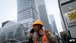 一名建筑工人在北京商业中心区的一个建筑工地旁打电话。(2024年10月31日)