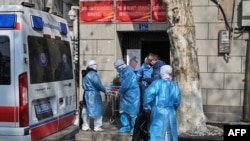 身穿防护服的医务人员把一名新冠病毒疑似感染的病人从武汉市一座居民楼里抬出。（2020年1月30日）