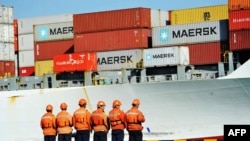 在美中两国开打贸易战的阴影下,中国工人站在山东省青岛港的一艘集装箱船旁(2018年4月8日)