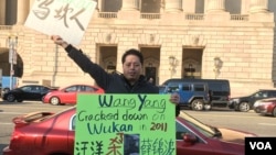 2016年11月23日,乌坎维权领袖庄烈宏在美中商贸联委会第27次会议的会场外手举抗议标语牌(美国之音莫雨拍摄)