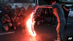 Một người biểu tình đốt cờ Mỹ bên ngoài đại sứ quán Hoa Kỳ ở Athens, Hy Lạp, hôm 14/4.