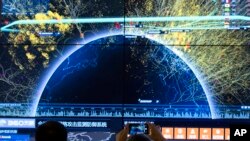 资料照 - 2016年8月16日在北京召开的第四届中国网络安全会议上,一位与会者正在用手机对全球网络攻击检测防御系统的视觉画面拍照。