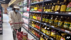 一名女子在北京一家超市里走过食用油货架。(2024年7月10日)