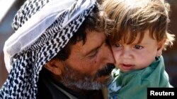 Một người tỵ nạn Syria Kurd bế một em bé sau khi băng qua biên giới Thổ Nhĩ Kỳ-Syria gần thị trấn miền đông nam Suruc, tỉnh Sanliurfa, 26/9/2014.