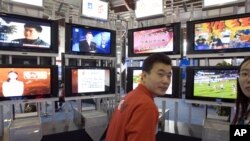 资料照:在2006年北京国际广播电影电视设备展上,一位男士站在一系列电视机前。