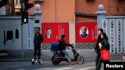 上海市民在张贴着中共领导人习近平和前领导人毛泽东的宣传画前走过。(资料照片)
