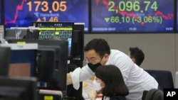 韩国首尔韩亚银行外汇交易处的货币交易员戴着口罩监看行情。(2020年2月24日)