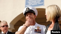 资料照片:美国海军三栖特种作战部队“海豹部队”军士爱德华·加拉格尔在加州圣迭戈海军基地的军法审判宣布他的多数罪名均不成立后,与妻子站在一起准备接受媒体问话。(2019年7月2日)